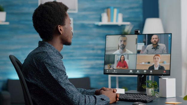 Mise au point sélective sur un homme afro-américain lors d'un appel vidéo de conférence en ligne