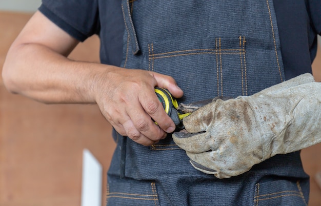 Mise au point sélective de l'homme charpentier avec ruban à mesurer à la main, concept de l'artisan.