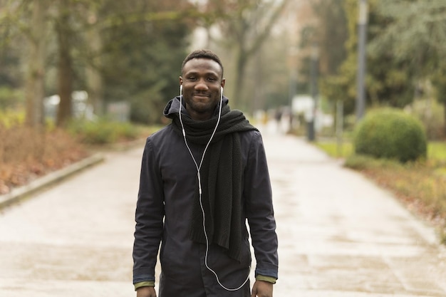 Mise au point sélective d'un homme noir souriant avec des écouteurs marchant dans les rues