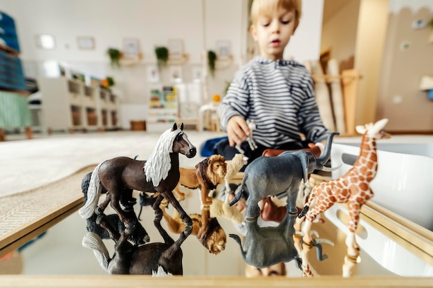 Mise au point sélective sur les jouets d'animaux avec un petit garçon jouant avec à la maternelle montessori
