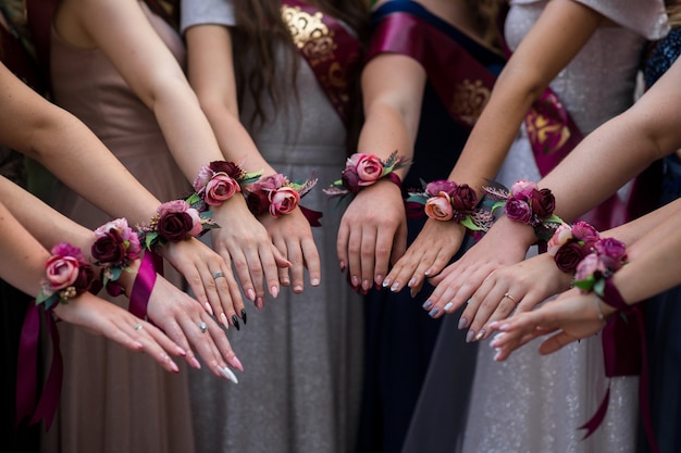 Mise au point sélective sur les mains d'un groupe de filles avec des boutannières. belles décorations florales pour les mains