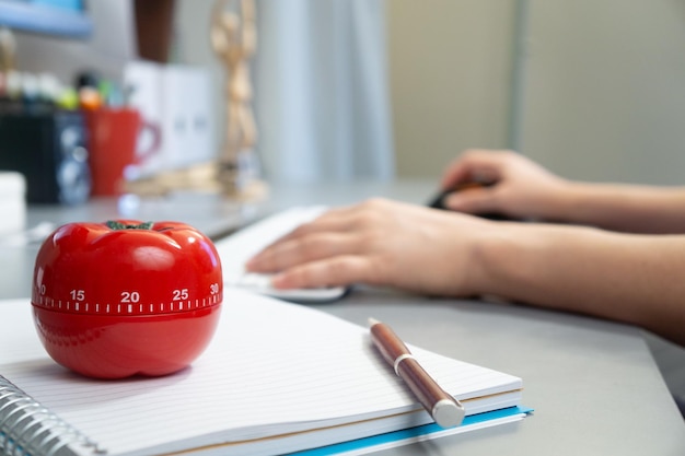 Mise au point sélective d'une minuterie de cuisine sous la forme d'une tomate sur un cahier