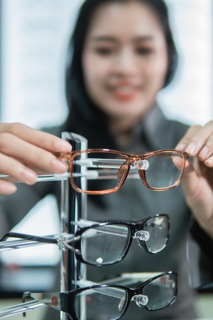 Mise au point sélective des montures de lunettes placées sur une étagère par une cliente après les avoir essayées chez un opticien