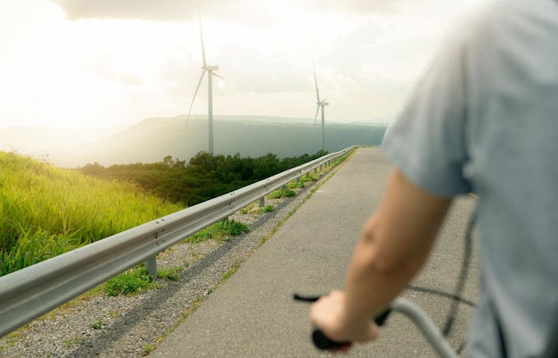 Mise au point sélective sur le parc éolien avec vue arrière d'une personne faisant du vélo au premier plan