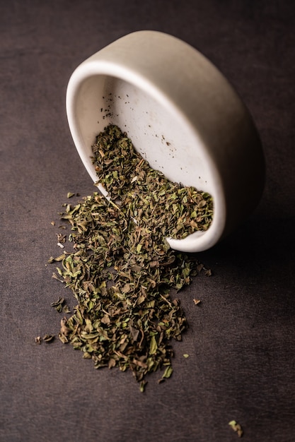 Mise au point sélective, thé vert naturel en feuilles. brasser dans un bol en argile. angle vertical, macro. sur fond sombre. pour les menus et les cafés