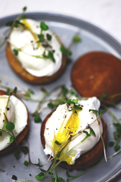 Mise au point sélective. Œufs pochés sur petits pains avec microgreens sur une assiette.