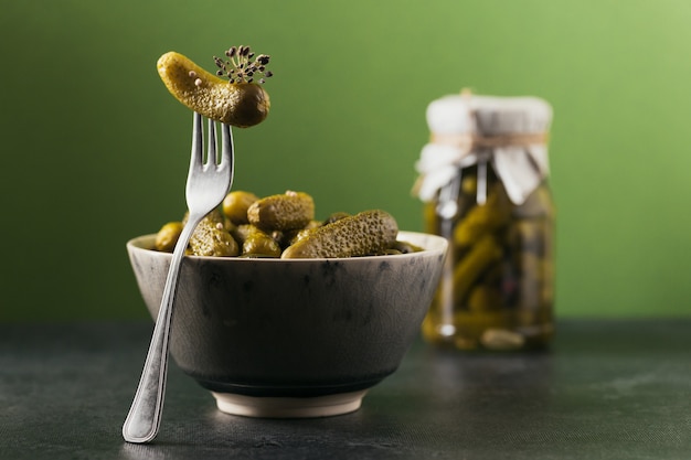 Mise en conserve maison. Cornichons de concombres marinés à l'aneth et à l'ail dans un bocal en verre sur fond vert. Salades de légumes pour l'hiver.