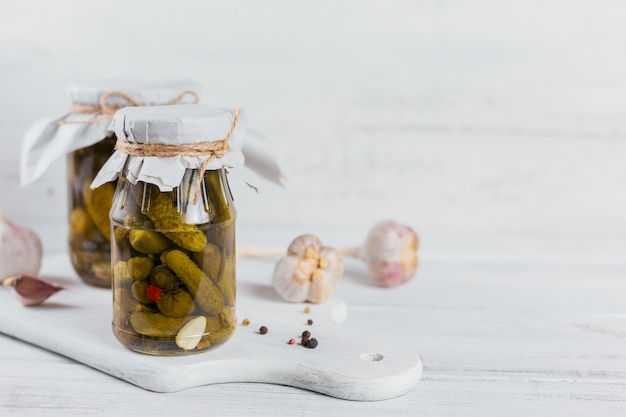 Mise en conserve maison. Cornichons de concombres marinés à l'aneth et l'ail dans un bocal en verre sur la table en bois blanc. Salades de légumes pour l'hiver.