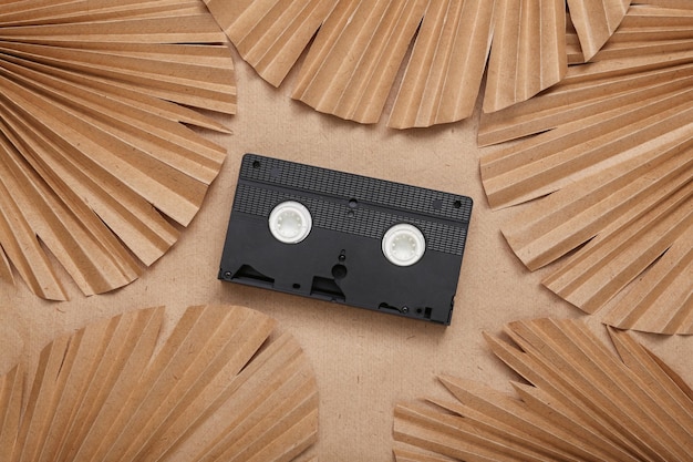 Mise en page créative Cassette vidéo Vhs et feuilles de palmier sur fond beige Mise à plat