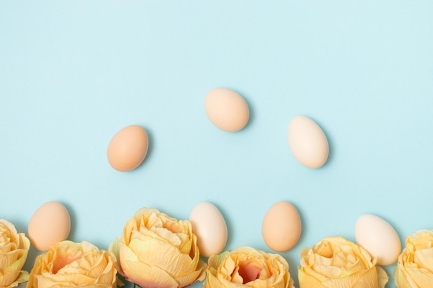 Mise en page créative faite avec des fleurs colorées et des oeufs de Pâques Fond de nature minimale