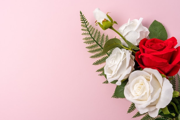 Mise en page créative faite avec des fleurs sur fond rose.