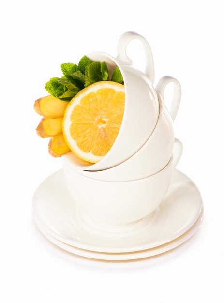 Mise en page créative faite de tasse de thé à la menthe, citron, gingembre sur fond blanc. Vue de dessus.