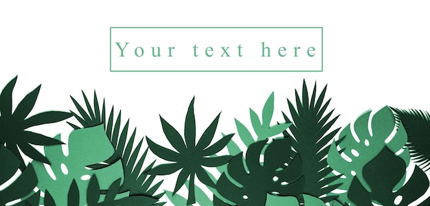 Mise en page créative des feuilles tropicales avec l'inscription "Votre texte ici". Vue d'en-haut. Concept de la nature.