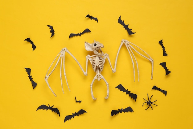 Mise en page créative d'halloween Squelette de chauve-souris vampire et chauves-souris volantes sur fond jaune Mise à plat Vue de dessus