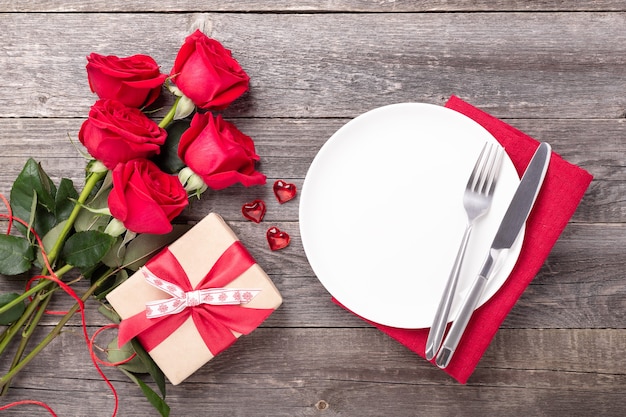 Mise en place de la Saint-Valentin avec bouquet de roses, coeurs rouges et argenterie sur table en bois gris. Vue de dessus. Copier l'espace - Image