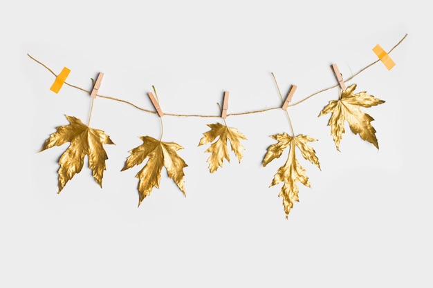 Mise à plat d'automne et d'automne avec des feuilles dorées matalliques peintes avec du ruban adhésif créatif sur l'espace de copie d'individualité de fond blanc