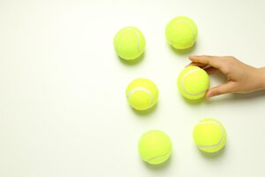 Photo mise à plat avec balles de tennis et main féminine sur fond blanc