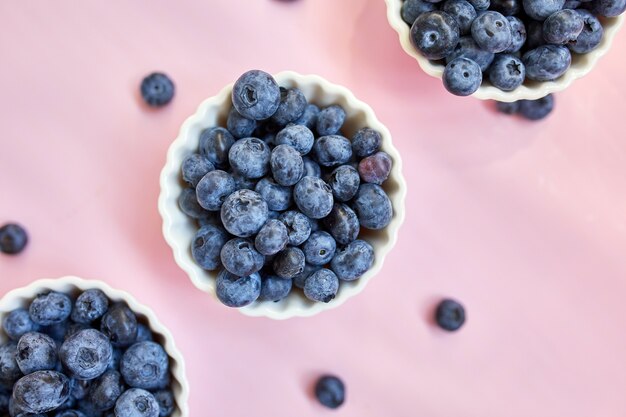 Mise à plat de bleuets frais et juteux biologiques dans un bol sur fond rose