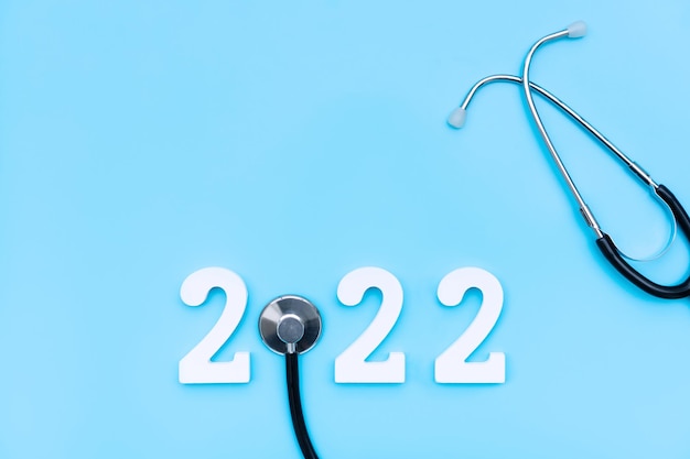 Mise à plat de la bonne année 2022. Numéro 2022 avec stéthoscope sur fond bleu. santé médicale et nouveau concept de mode de vie normal. Espace de copie, vue de dessus