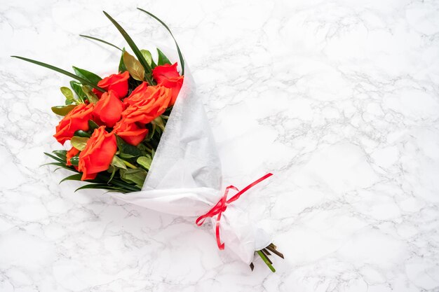 Mise à plat. Bouquet de roses rouges et de feuilles vertes sur fond de marbre.