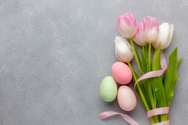 Photo mise à plat de bouquet de tulipes avec des oeufs de pâques colorés