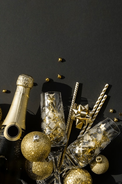 Photo mise à plat d'une bouteille de champagne avec des confettis et des boules de verres en cristal