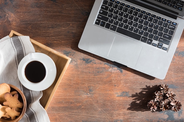 Mise à plat d'une branche de sapin de Noël, d'un homme en pain d'épice, d'une tasse à café et d'un clavier d'ordinateur ou d'ordinateur portable sur fond en bois. Vue de dessus en toile de fond hiver, noël et nouvel an avec un espace pour le texte