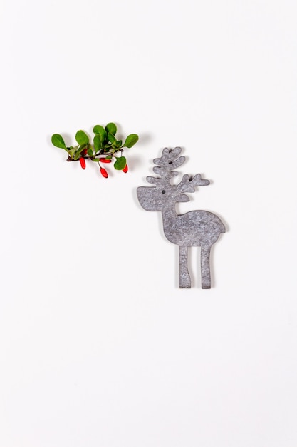 Mise à plat créative de petit cerf et branche d'épine-vinette sur fond clair vue d'en haut noël nouvel an et concept de vacances