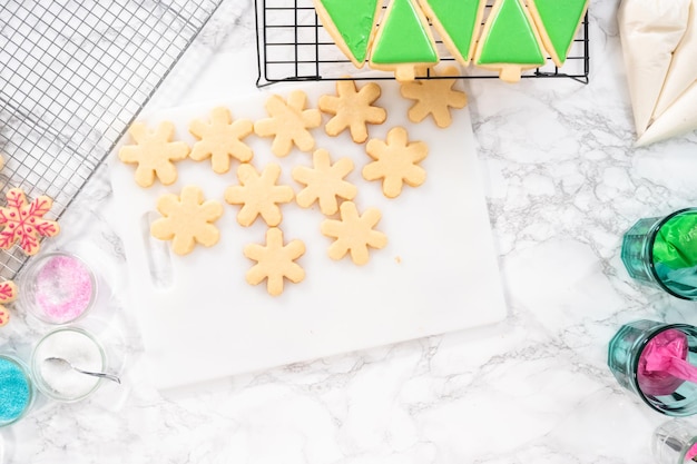 Mise à plat. Décorer des biscuits au sucre de Noël avec du glaçage royal et des vermicelles.