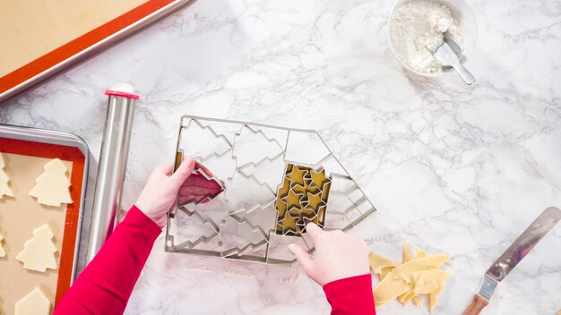 Mise à plat. Découper des biscuits au sucre avec un emporte-pièce géant de Noël.