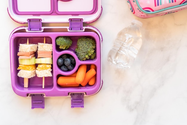 Mise à plat. Déjeuner scolaire sain avec sandwich kebab et légumes dans une boîte à bento.