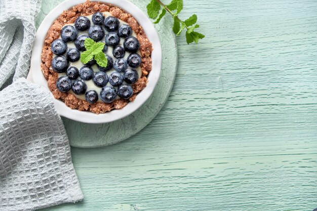 Mise à plat de délicieuses tartelettes aux bleuets avec crème pâtissière à la vanille et feuille de menthe