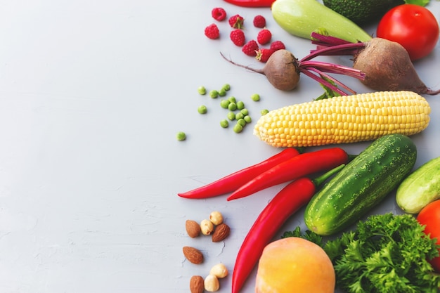 Mise à plat avec différents légumes, fruits, baies, noix, épices, herbes, huile d'olive. Copiez la zone d'espace pour du texte. Légumes sur fond de béton gris. Concept d'alimentation saine bio bio alimentaire