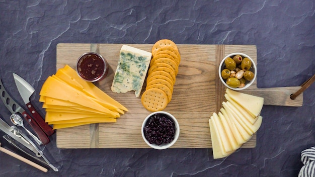 Mise à plat. Disposer du fromage gastronomique, des craquelins et des fruits sur une planche pour un grand plateau de fromages.