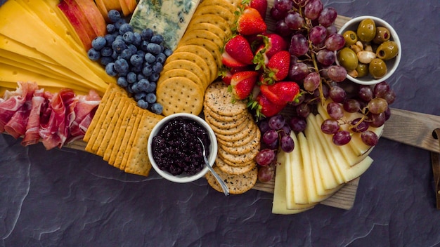 Mise à plat. Disposer du fromage gastronomique, des craquelins et des fruits sur une planche pour un grand plateau de fromages.