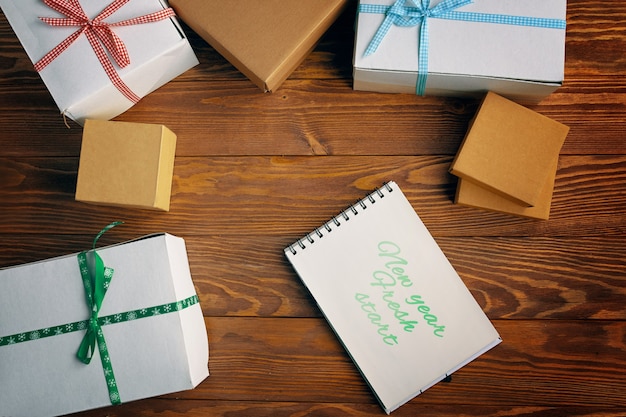 Mise à plat du bloc-notes de motivation et des coffrets cadeaux sur fond de table en bois nouvel an nouveau départ christma...