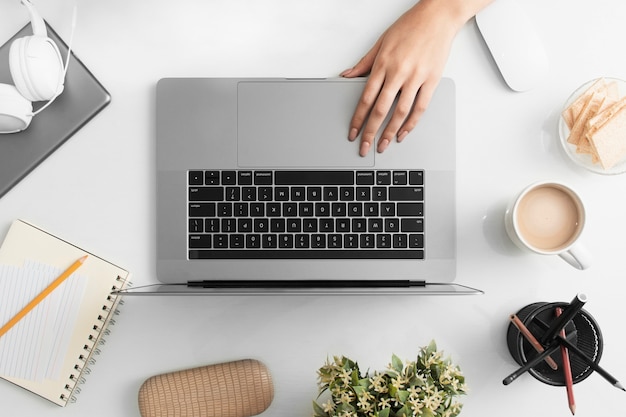 Mise à plat du bureau avec la main et l'ordinateur portable