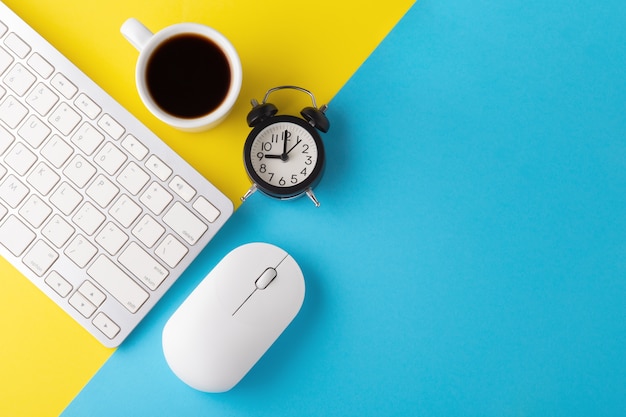 Mise à plat du clavier et de la souris d'ordinateur avec horloge et tasse de café