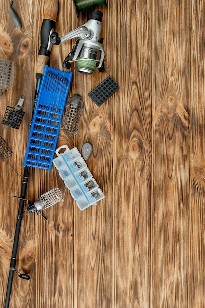 Mise à plat avec du matériel de pêche canne à pêche et boîte en plastique avec du matériel de pêche et des mangeoires à crochets sur des planches de bois copiez l'espace