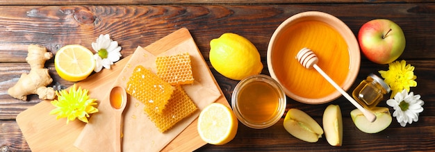 Mise à plat avec du miel, des fleurs et des fruits sur fond de bois