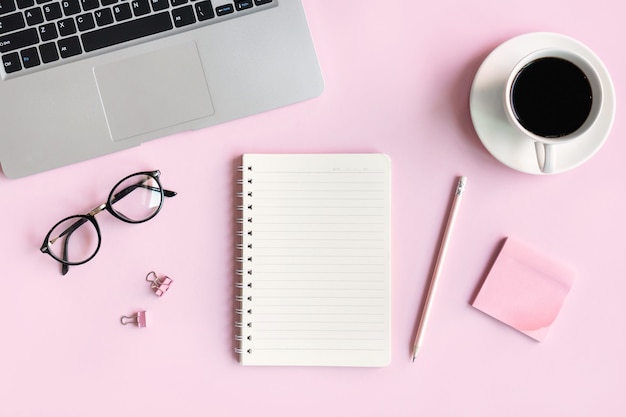 Mise à plat du téléphone mobile, une tasse de café, des verres et de la papeterie de bureau de femme d'affaires sur rose