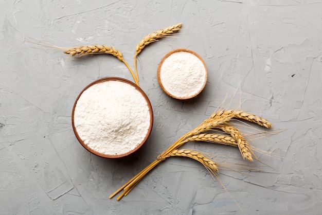 Mise à plat de farine de blé dans un bol en bois avec des épillets de blé sur fond coloré crise mondiale du blé