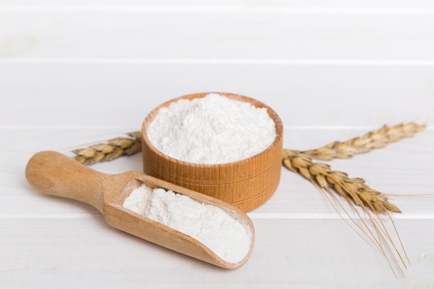 Mise à plat de farine de blé dans un bol en bois avec des épillets de blé sur fond coloré crise mondiale du blé