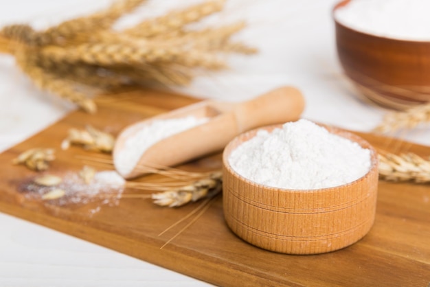 Mise à plat de farine de blé dans un bol en bois avec des épillets de blé sur fond coloré crise mondiale du blé