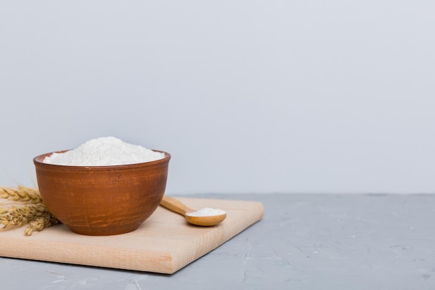 Mise à plat de farine de blé dans un bol en bois avec des épillets de blé sur fond coloré crise mondiale du blé