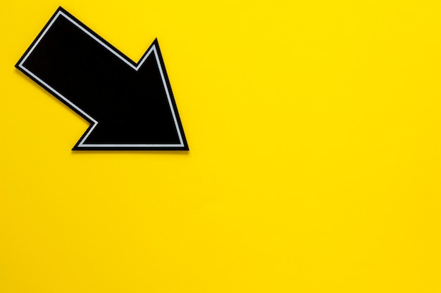 Mise à plat flèche noire sur fond jaune avec copie-espace