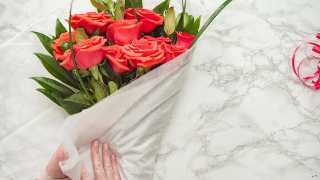 Mise à plat. Fleuriste emballant des roses rouges dans un beau bouquet.