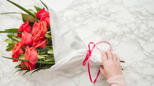 Mise à plat. Fleuriste emballant des roses rouges dans un beau bouquet.