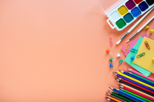 Mise à plat de fournitures scolaires sur fond de couleur.