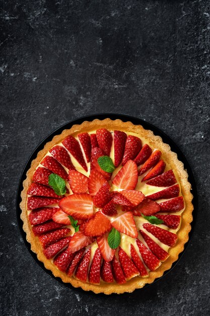 Mise à plat de gâteau aux fraises fraîches sur fond noir